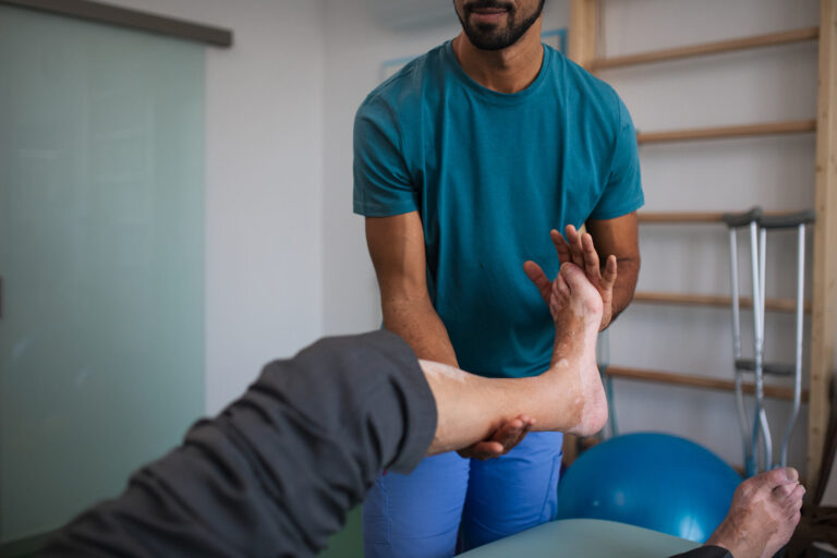 Physiotherapeut in Mettmann mobilisiert das Sprunggelenk eines Patienten.