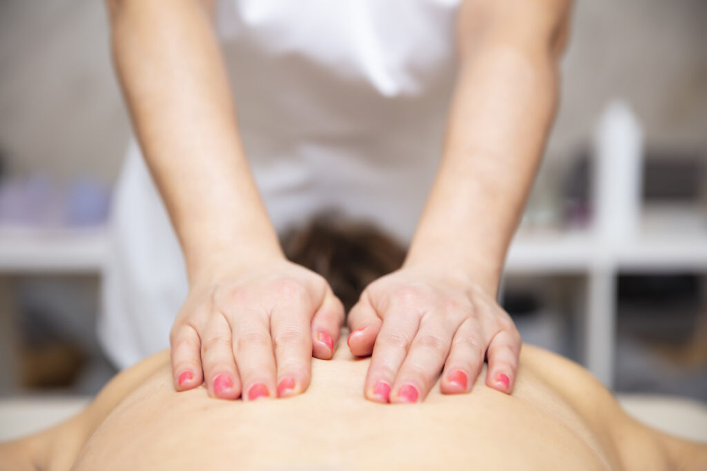 Therapeutische Massage am Rücken, bei der der Therapeut mit gezieltem Druck verspannte Muskulatur behandelt.